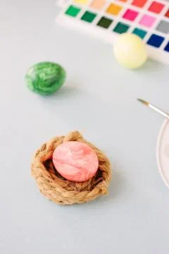 Pink color egg on bright background. Nest and easter. Stock Photos