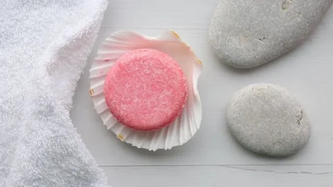 Pink color solid shampoo, conditioner bar on flat sea stones. Stock Footage 166065810