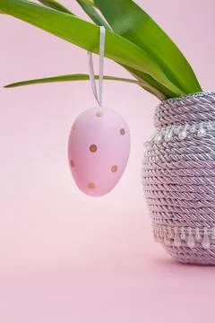 Pink colored egg hangs on leaves. Bouquet in vase. Easter. Copy space Стоковые фото
