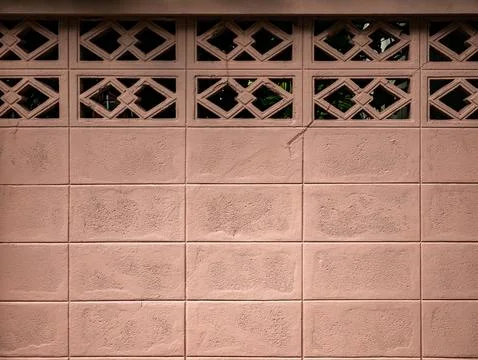 Pink Concrete Diamond Pattern Breeze Block Wall with Green Foliage Stock Photos