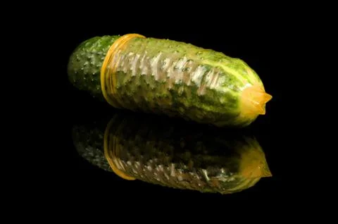 Pink condom pulled on cucumber isolated on the black Stock-Fotos
