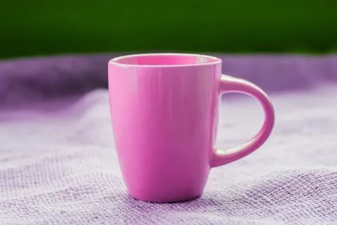 Pink cup on the table by the window on sackcloth isolated, with a hot drink i Stock Photos
