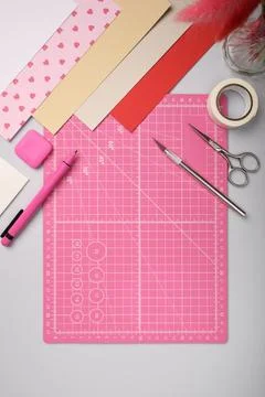 Pink cutting mat surrounded by colored paper and craft tools on desk. Creat.. Stock Photos