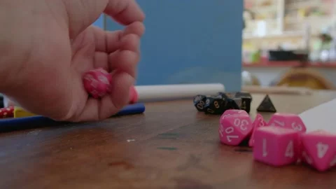 A pink d20, or twenty-sided die being rolled during a roll playing game Stock Footage 209424835
