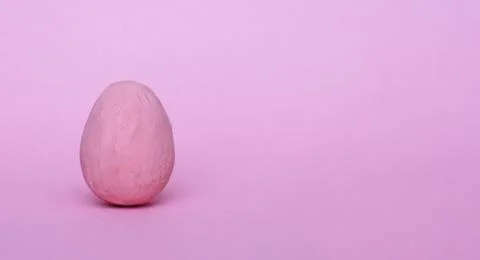 Pink decorative Easter egg on a light red background. Stock Photos