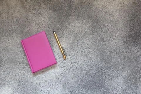 Pink diary on gray concrete background and golden elegant pen. Foto stock