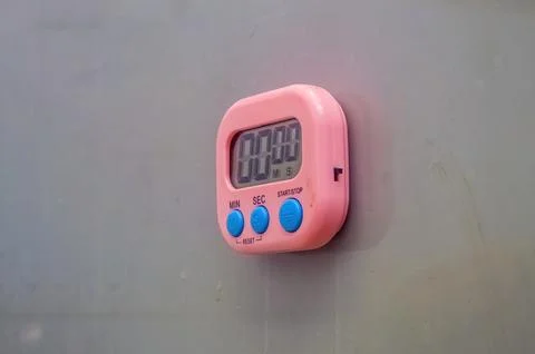 A pink digital timer stuck to the gray wall Stock Photos