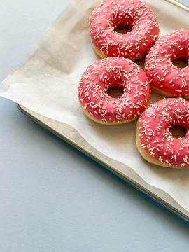 Pink donuts on metal tray and blue background with copy space Stock Photos
