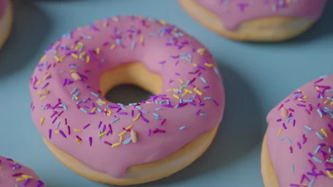 Pink donuts with rainbow sprinkles on a blue background Stock Footage 255720853