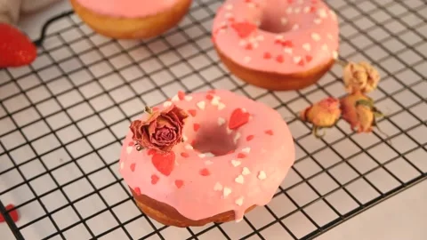 Pink doughnuts on the baking rack. Valentine's Day concept. Woman hand take a Stock Footage 145122273
