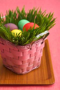 Pink Easter Basket Filled with Grass and Colored Easter Eggs Stock Photos