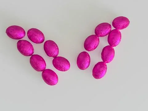 Pink Easter Chocolate Eggs Forming Bunny Ears on White Background Stock Photos