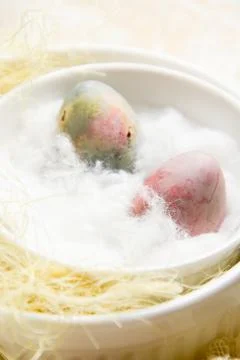 Pink Easter egg close-up on a soft cotton pad in a white round bowl on a pastel Stock Photos