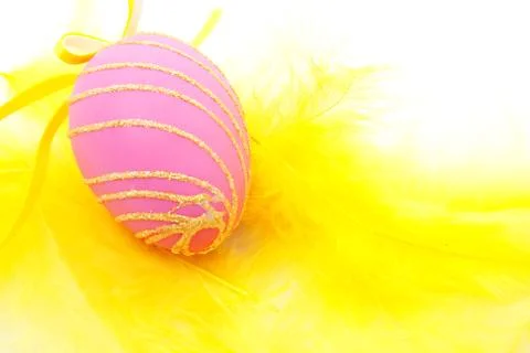 Pink easter egg on yellow feathers Stock Photos