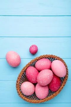 Pink easter eggs in basket on blue wooden background Stock Photos