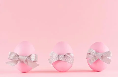 Pink easter eggs with grey bows standing in row on pastel pink background. Foto stock