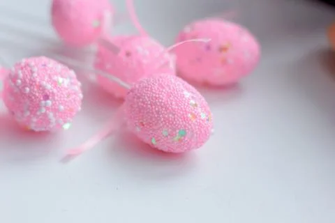 Pink easter eggs on a sticks over the white table. Stock Photos