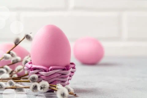 Pink Easter eggs in a wicker stand and on a gray table with pussy-willow twig Stock Photos