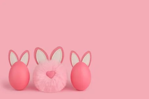 Pink Easter fluffy bunny and two eggs with ears on a pink background. Stock Photos