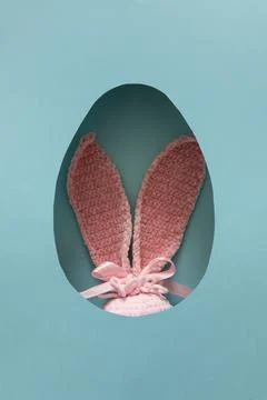 Pink Easter plush bunny ears peeking through oval egg shaped cutout in past.. Foto stock