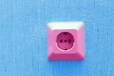 Pink electric socket on blue wall Stock-Fotos