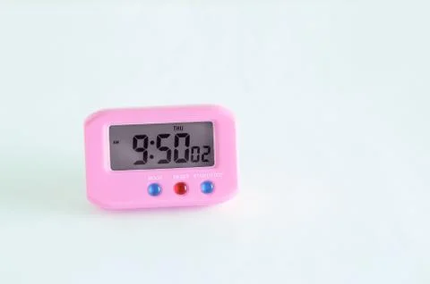 Pink electronic clock on a white background. Close-up. Stock Photos