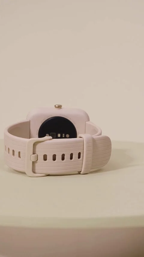 Pink electronic smartwatch rotating on a neutral colored surface Video stock 331773866