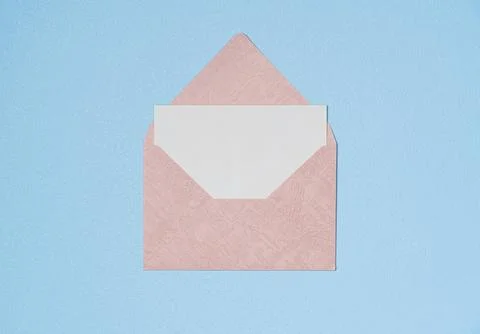 Pink envelope and empty white paper list on blue background from above. Copy  Stock Photos