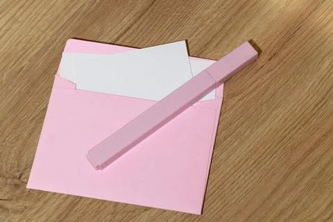 Pink envelope with blank white card and pastel marker on a wooden desk Stock Photos
