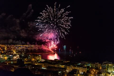 Pink exploding firework near the harbor of a coastal city Stock Photos