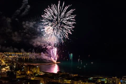 Pink exploding fireworks near the harbor of a coastal city Stock Photos