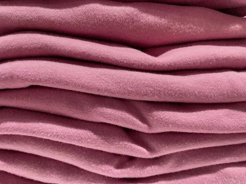 Pink fabric as background, stack of clothes, close-up 스톡 사진