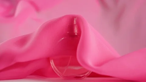 Pink fabric flutters around and waves in the air around the bottle with perfumes Stock Footage