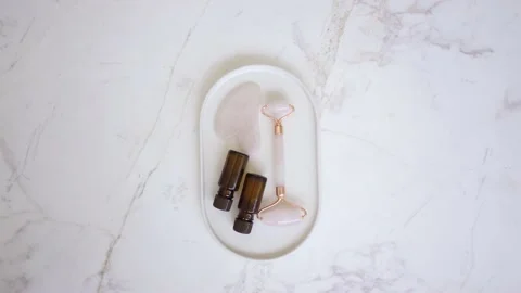 Pink face roller and jade roller laying on white background. Beauty roller tools Stock Footage 142200561