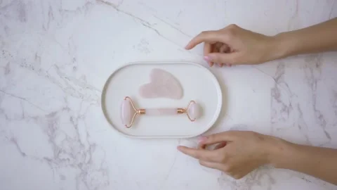 Pink face roller and jade roller laying on white background. Beauty roller tools Stock Footage 142200685