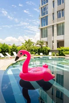 A pink flamingo pool float is floating in a pool. Vertical shot 写真素材