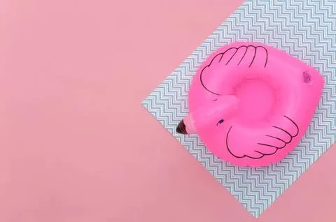 Pink flamingo pool float on zigzag patterned mat on pink background Stock Photos