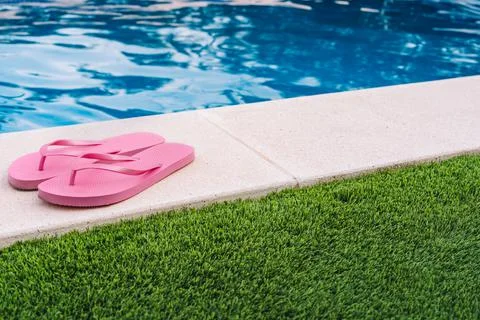 Pink flip flops for pool or beach on grass with pool bottom. Pool water texture Stock Photos
