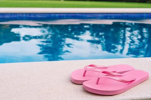 Pink flip flops for pool or beach on grass with pool bottom. Pool water texture Stock Photos