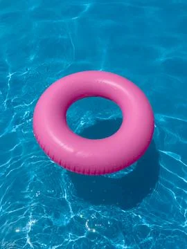 Pink float ring in clear swimming pool water on a sunny day Stock Photos