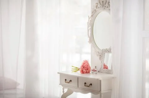  Pink flowers on the dressing table in the white bedroom. Flowers and perfumes i Stock Photos