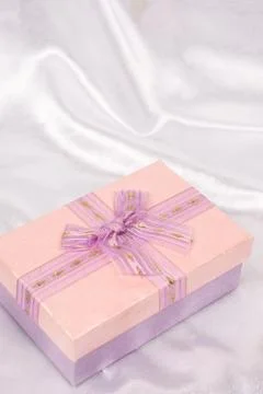 Pink gift box with bow over white satin Stock Photos