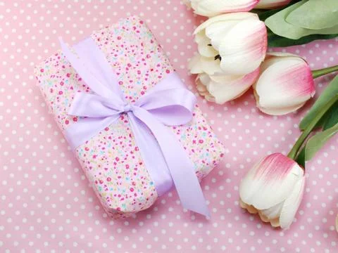 Pink gift box with bow present and tulip artificial flowers on pink polka dot 스톡 사진