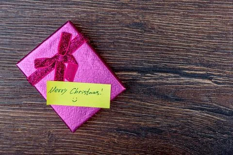 Pink gift box with handwritten note Merry Christmas on wooden background. Stock Photos