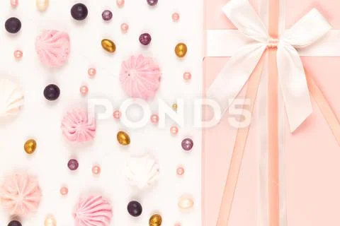 Pink gift box with scattered sweets and bizet cake on a white wooden table Stock Photos