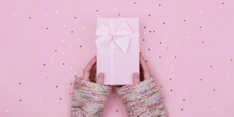Pink Gift or present box in woman hand with stars confetti on pink background Stock Photos