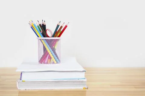 Pink glass with colored pencils on a stack of books. copy space.. Stock Photos