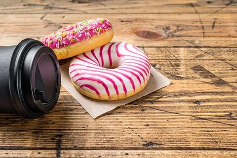 Pink glazed donuts on a kitchen table with coffee. Wooden background. Top view Stock Photos