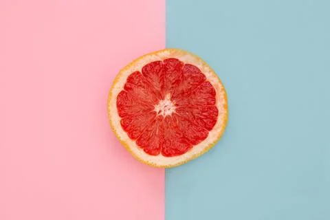Pink grapefruit on bright pink and blue background Stock Photos