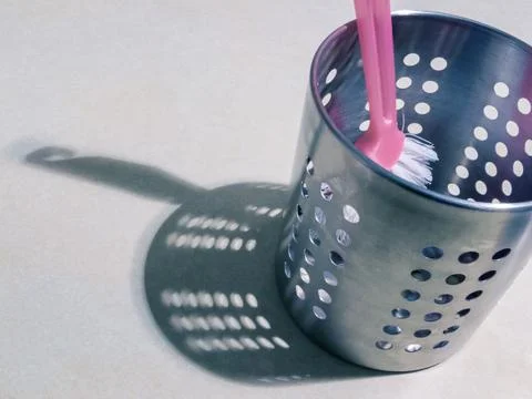 Pink handled kitchen scrub brush inside silver aluminum metal container. Stock Photos
